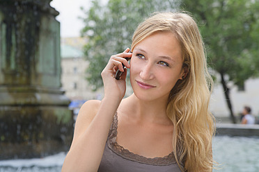 Deutschland, Bayern, München, Junge Frau telefoniert vor der Ludwig-Maximilians-Universität - TCF002800