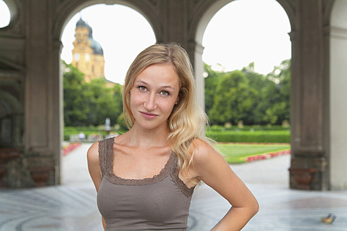 Deutschland, Bayern, München, Junge Frau vor der Theatinerkirche stehend, lächelnd, Porträt - TCF002802