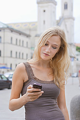 Deutschland, Bayern, München, Junge Frau mit Smartphone vor der Ludwig-Maximilians-Universität - TCF002805