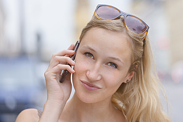 Germany, Bavaria, Munich, Young woman talking on phone in front of Bavarian State Library at Ludwigstrasse - TCF002812