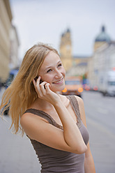 Deutschland, Bayern, München, Junge Frau mit Smartphone vor der Bayerischen Staatsbibliothek in der Ludwigstraße - TCF002816