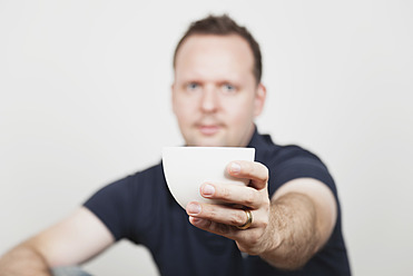 Mid adult man offering coffee, portrait - GWF001859