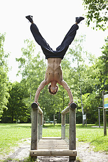 Germany, Bavaria, Young man doing handstand on railing - MAEF004781