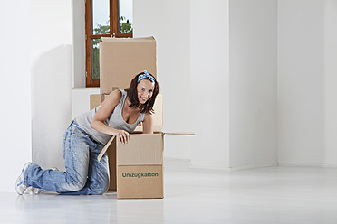 Young woman packing cardboard box, smiling, portrait - MAEF004731