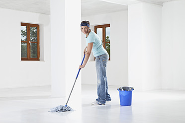 Germany, Bavaria, Young woman mopping floor, smiling, portrait - MAEF004716