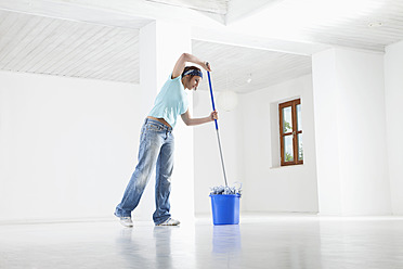 Germany, Bavaria, Young woman mopping floor - MAEF004771