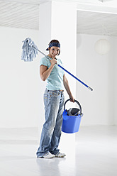 Germany, Bavaria, Young woman mopping floor, smiling, portrait - MAEF004772