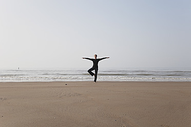 Belgien, Junge Frau in Baum-Pose an der Nordsee - GWF001860