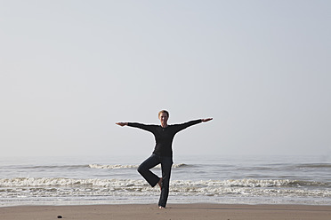 Belgien, Junge Frau in Baum-Pose an der Nordsee - GWF001861