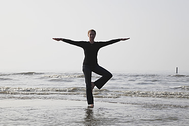 Belgien, Junge Frau in Baum-Pose an der Nordsee - GWF001868