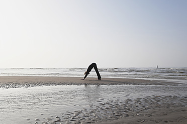 Belgium, Young woman exercising at North Sea - GWF001870