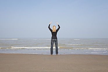 Belgien, Junge Frau meditiert an der Nordsee - GWF001874