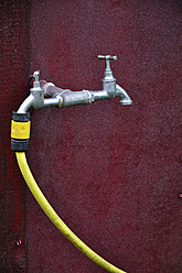 Germany, Bavaria, Water tap with yellow garden hose - AXF000147