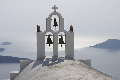 Griechenland, Glockenturm der weiß getünchten Kirche in Imerovigli, Meer im Hintergrund auf Santorin, lizenzfreies Stockfoto