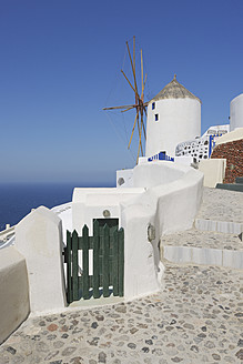Griechenland, Windmühle mit gepflastertem Weg und grünem Tor im traditionell griechischen Dorf Oia auf Santorin - RUEF000979