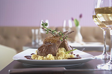 Teller mit Lammkarree mit Couscous und Wein auf dem Tisch - KSWF001003