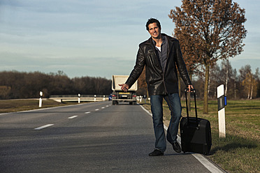 Germany, Bavaria, Munich, Mid adult man hitchhiking on road - RDF001002