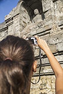 Indonesien, Junge Frau fotografiert Buddha-Statue im Borobudur-Tempel - MBEF000409