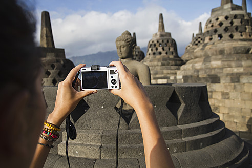 Indonesien, Junge Frau fotografiert Buddha-Statue im Borobudur-Tempel - MBEF000411