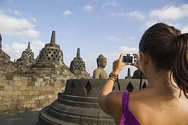 Indonesien, Junge Frau fotografiert Buddha-Statue im Borobudur-Tempel - MBEF000407