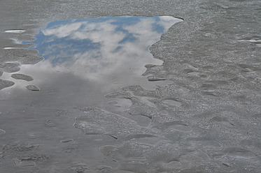 Deutschland, Bayern, Gefrorener See mit Spiegelung von Himmel und Wolken - AXF000173