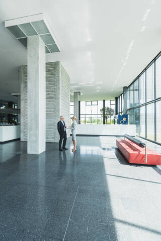 Deutschland, Stuttgart, Geschäftsleute im Gespräch in der Büro-Lobby, lizenzfreies Stockfoto