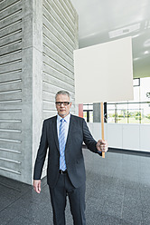 Deutschland, Stuttgart, Geschäftsmann hält Plakat in Bürohalle - MFPF000239