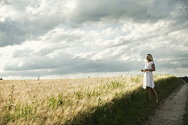 Germany, Bavaria, Mature woman standing in grain field - RNF000964