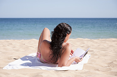 Portugal, Lagos, Mittlere erwachsene Frau liest Buch am Strand - UMF000352