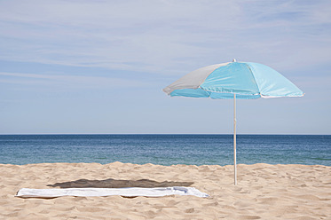 Portugal, Lagos, Strandhandtuch und Sonnenschirm am Strand - UMF000354
