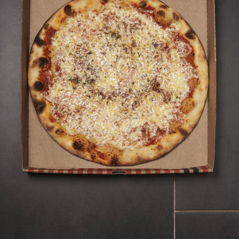 Pizza with cheese, tomato sauce and oregano in pizza box stock photo