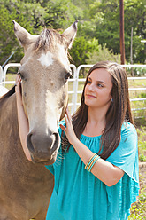 USA, Texas, Jugendliches Mädchen streichelt Pferd, lächelnd, Porträt - ABAF000148