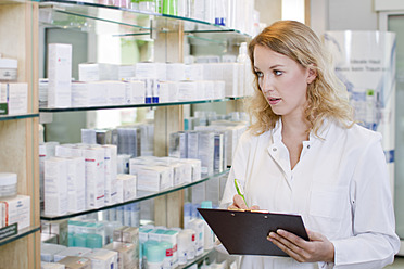 Deutschland, Brandenburg, Apothekerin prüft Produkte in der Apotheke - FKF000006