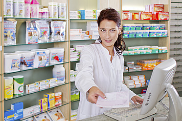 Germany, Brandenburg, Pharmacist holding prescription, smiling, portrait - FKF000010