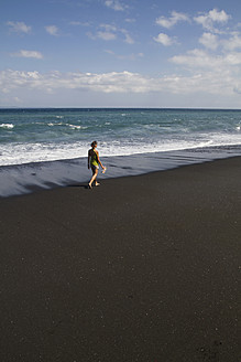 Indonesien, Junge Frau läuft auf schwarzem Sand - MBEF000415