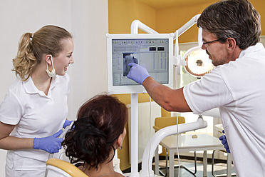 Germany, Brandenburg, Strausberg, Dentist and nurse explaining x ray picture to patient - FKF000039