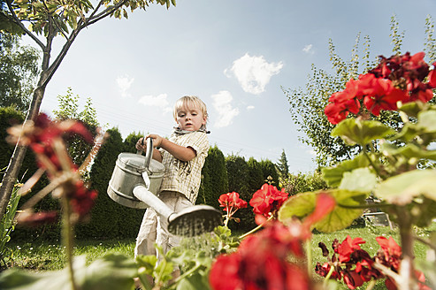 Germany, Bavaria, Boy watering garden flowers - RNF000976