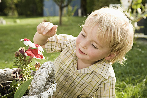 Deutschland, Bayern, Junge schnuppert an Blume, lächelnd - RNF000981