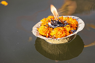India, Uttar Pradesh, Leaf bowl with oil lamp floating on river Ganges - FOF004180