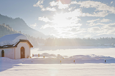 Österreich, Blick auf kleine Kapelle mit Gegenlicht in Winterlandschaft bei Saalbach - FLF000128