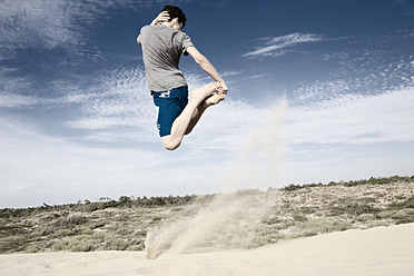 France, Teenage boy jumping on sand dune - MSF002749