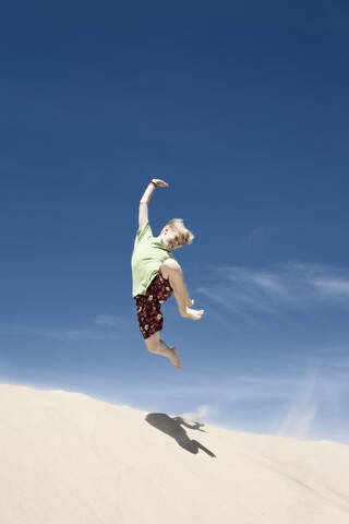 Frankreich, Junge springt auf Sanddüne, lizenzfreies Stockfoto