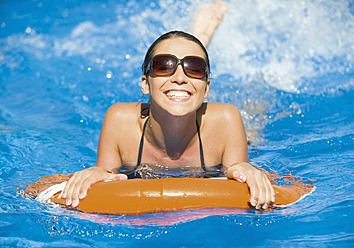 Deutschland, Junge Frau im Schwimmbad mit Rettungsring, lächelnd - WBF001392
