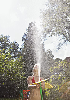 Deutschland, Mädchen, das mit einem Gartenschlauch Wasser versprüht - WBF001472