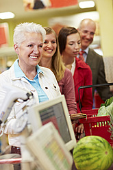 Deutschland, Köln, Mann und Frauen warten im Supermarkt - RKNF000041