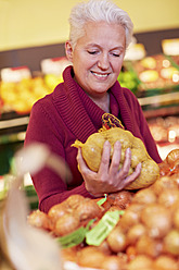 Deutschland, Köln, Reife Frau hält Kartoffelsack im Supermarkt - RKNF000078