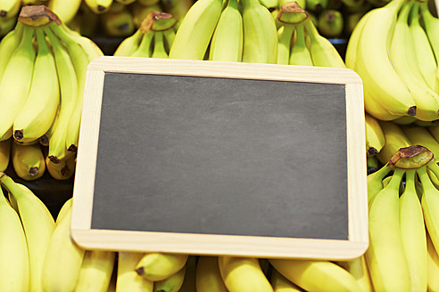Germany, Cologne, Bananas with blackboard in supermarket, close up - RKNF000092