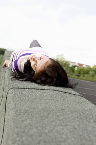 Germany, Hamburg, Young woman lying on wall stock photo