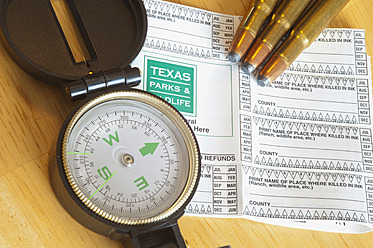 USA, Texas, Jagdschein mit Kompass und Kugeln auf Tisch - ABAF000216