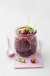 Jar of wild strawberry jam with spoon on white background - ECF000082